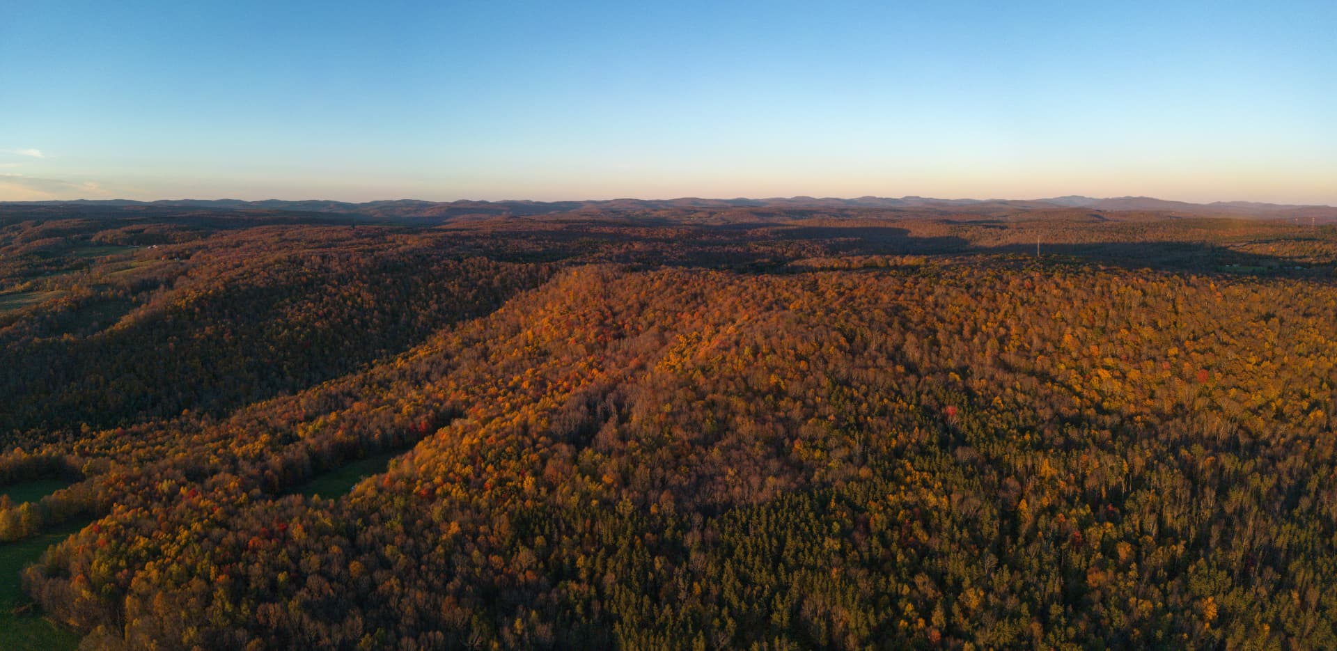 Aerial view of the Liberty, NY festival grounds with forest, pond, and rolling hills